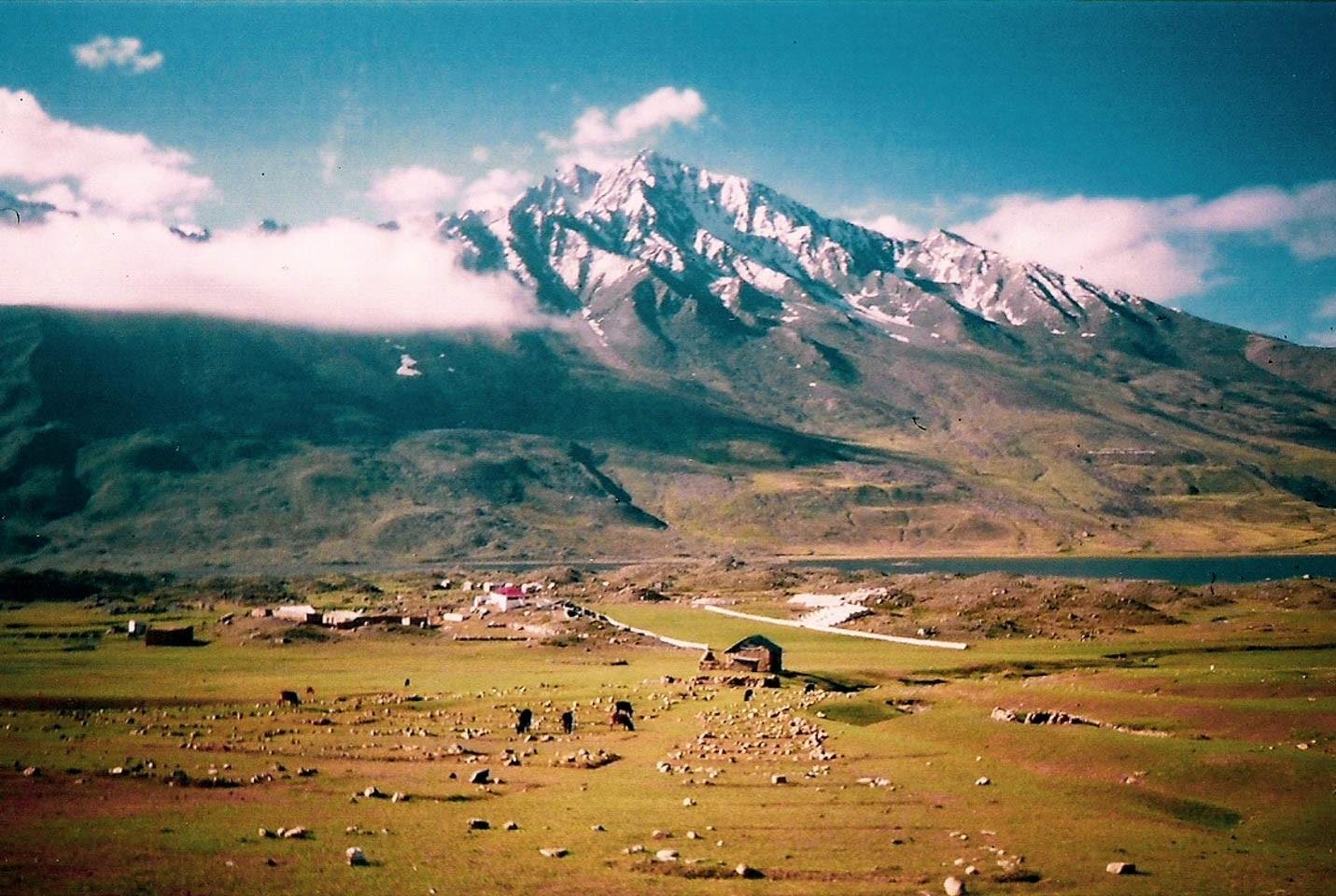 Summer landscape of Shandur National Park with snowcapped mountains and green meadows, showing the best season to visit