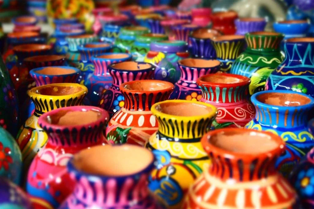 Close-up view of vibrant hand-painted clay pots in various colors and patterns, showcasing traditional Pakistani craftsmanship and artistic detail