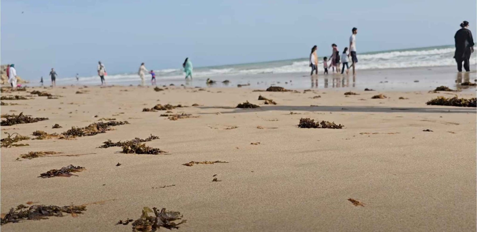 Tourists walking on golden sands and enjoying the water at Kund Malir Balochistan
