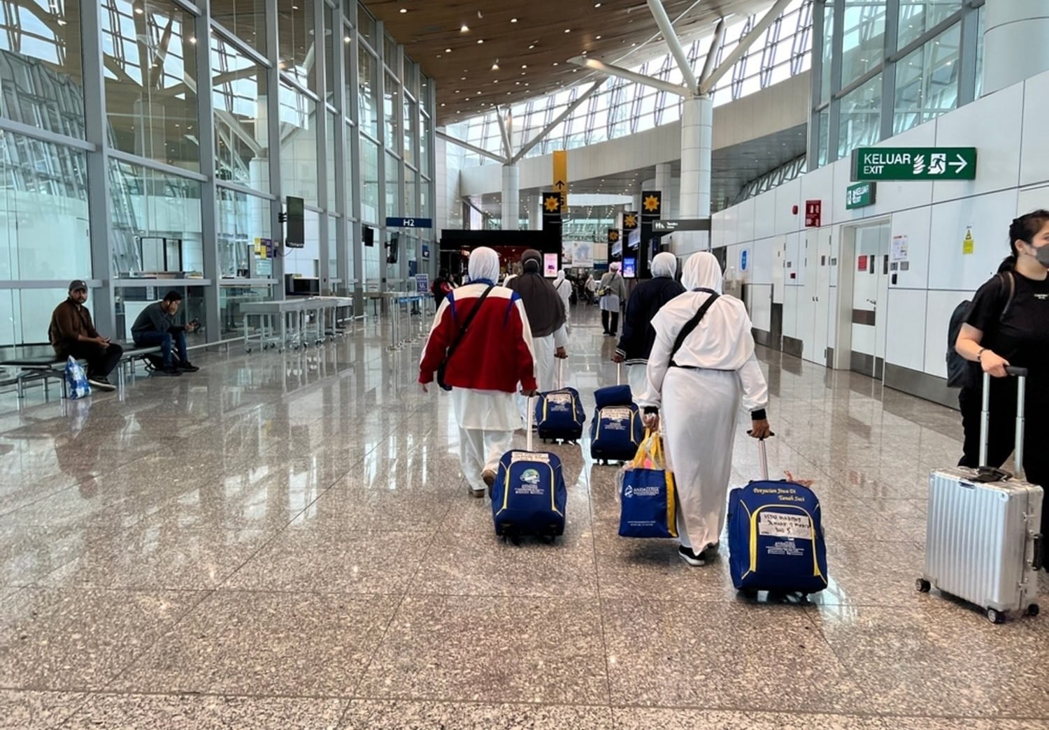 Pakistani pilgrims in Ihram clothing at airport traveling for Hajj with agency-arranged package services